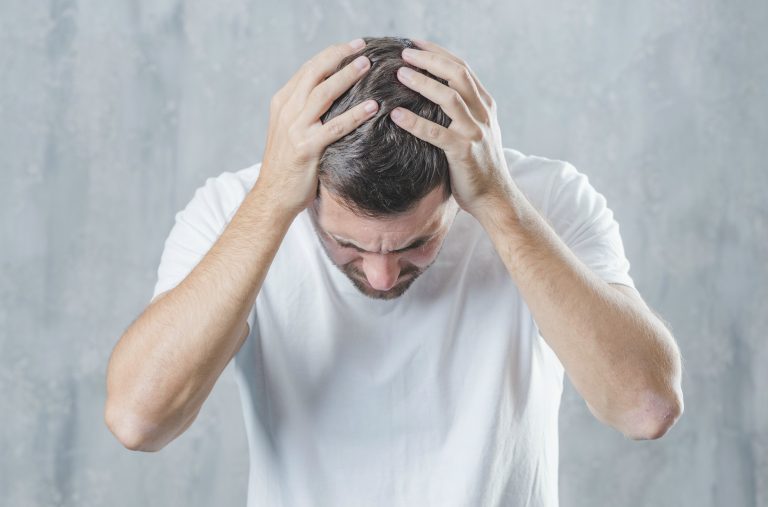 Homem sentindo fortes dores de cabeça, sintomas da esquizofrenia